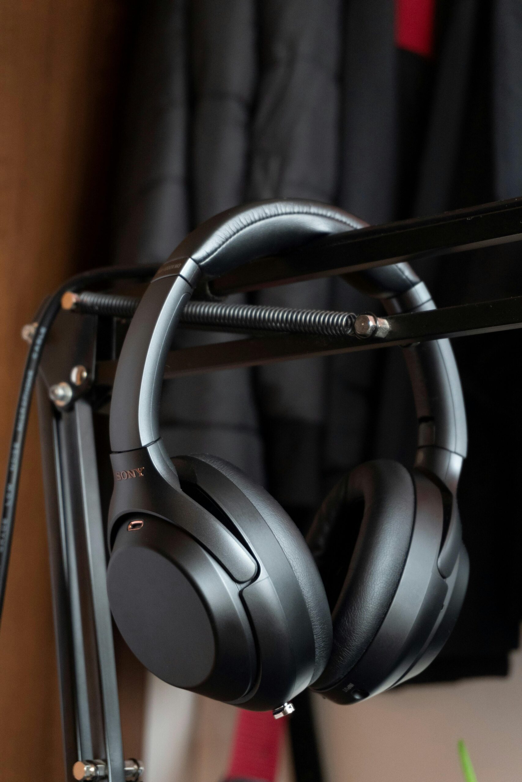 Close-up of modern black wireless headphones hanging indoors.